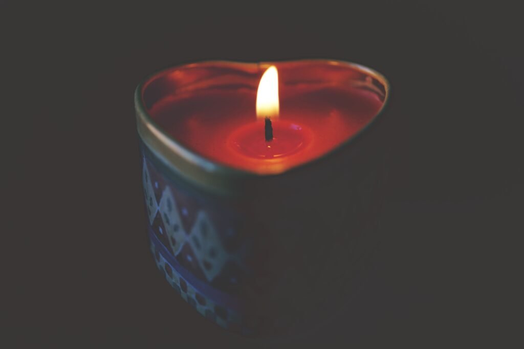 Heart-shaped candle with warm, glowing flame creating a romantic atmosphere.